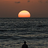 Evening Dip Photo: A surfer watches the setting sun slowly slip from view.