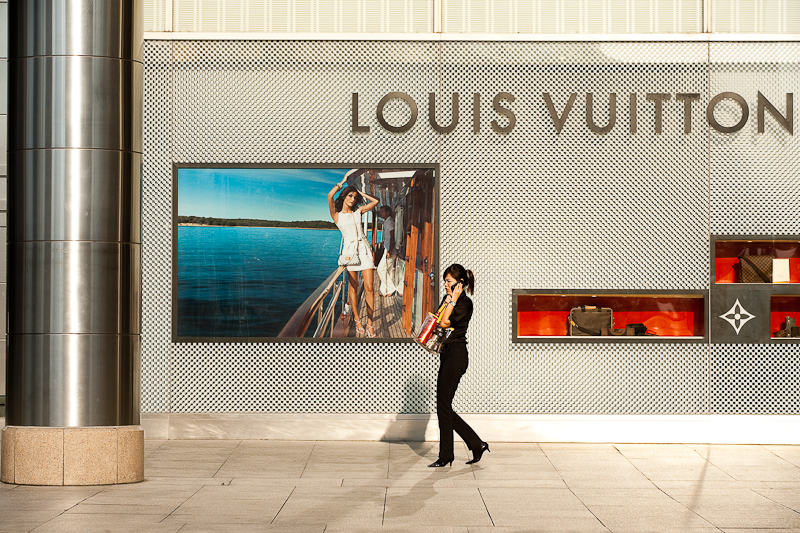 An ethnic Chinese-Malaysian woman walks in front of a Louis Vuitton store. - Kuala Lumpur, Malaysia - Daily Travel Photos