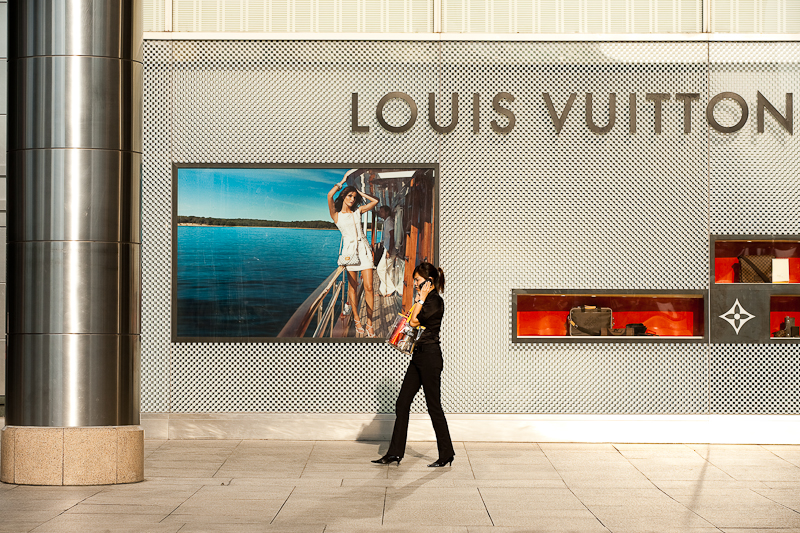 An ethnic Chinese-Malaysian woman walks in front of a Louis Vuitton store. - Kuala Lumpur, Malaysia - Daily Travel Photos