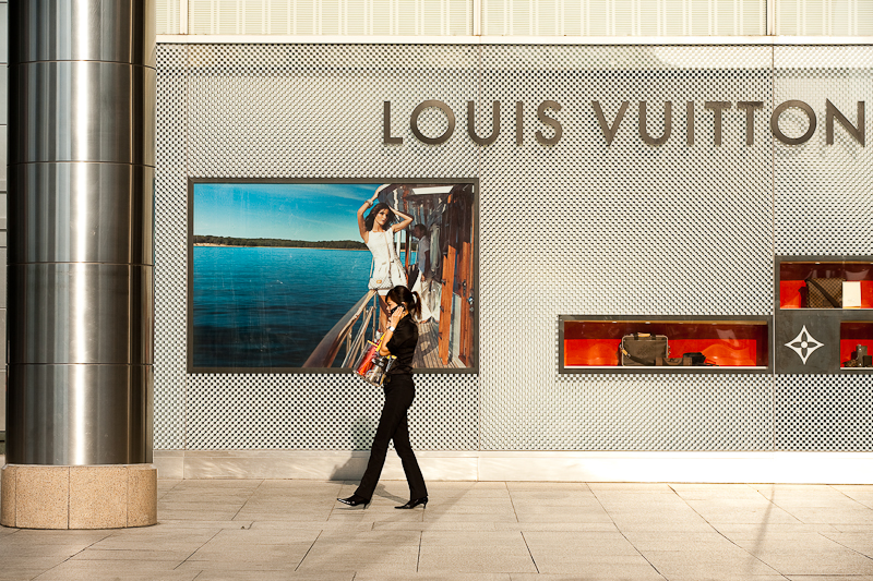 An ethnic Chinese-Malaysian woman walks in front of a Louis Vuitton store. - Kuala Lumpur, Malaysia - Daily Travel Photos