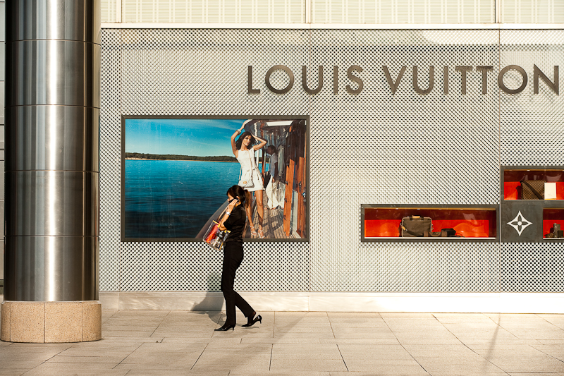 An ethnic Chinese-Malaysian woman walks in front of a Louis Vuitton store. - Kuala Lumpur, Malaysia - Daily Travel Photos