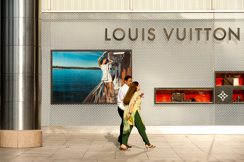 A pair of ethnic Indian-Malaysians walk in front of a Louis Vuitton store. - Kuala Lumpur, Malaysia - Daily Travel Photos