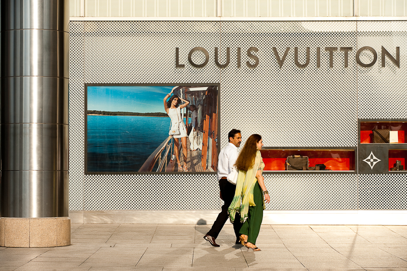 A pair of ethnic Indian-Malaysians walk in front of a Louis Vuitton store. - Kuala Lumpur, Malaysia - Daily Travel Photos