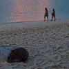 Wooded Photo: Vacationers walk the beach at sunset.