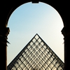 Louvre Leave Photo: People walk through an archway into the courtyard of the Louvre museum. 